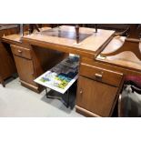 An Art Deco two pedestal desk with central raised section to top, pedestals fitted cupboards, 62"