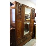 A late Victorian walnut wardrobe, fitted centre mirror door, two side doors inset carved panels,