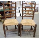 A pair of oak ladder back chairs with rush envelope seats, on turned and stretchered supports