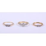 An 18ct gold diamond solitaire ring, size M, an 18ct gold and diamond three stone dress ring, size