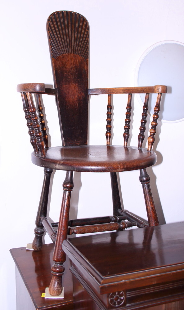 A late 19th century oak splat back elbow chair with circular panel seat, on turned and stretchered