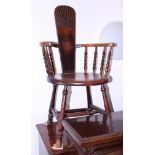 A late 19th century oak splat back elbow chair with circular panel seat, on turned and stretchered
