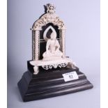 A 19th century Oriental carved ivory figure of a seated Buddha within a shrine, on ebonised mount, 8