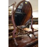 A mahogany oval swing frame toilet mirror, on skeleton stand, 20" wide