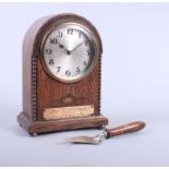 An early 20th century oak cased mantel clock with silvered dial and Masonic inscription and a