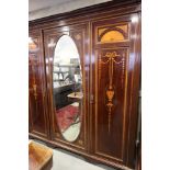 An Edwardian mahogany three door wardrobe, fitted centre mirror door and side doors decorated inlaid