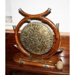 A late 19th century oak and brass dinner gong and beater with carved supports, in the form of a pair