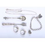 A white metal coffee spoon with figure finial, a silver pickle fork, two silver rings, a silver