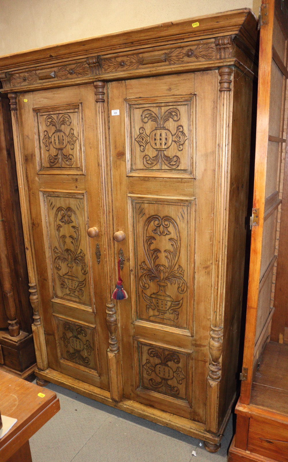 A late 19th century stripped pine armoire enclosed two carved doors and split turned columns, on bun