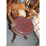 An early 20th century wooden office chair with circular seat and cushion, on swivel base, fitted