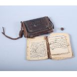 A Middle Eastern book with hand-written pages in Arabic script, in tooled leather pouch