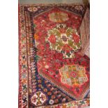 A Persian rug decorated three ivory medallions on a red floral ground and border with blue