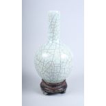 A Chinese celadon crackle glaze pottery bottle vase, on integral shaped hardwood stand, 13" high