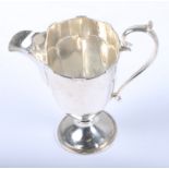 A Walker & Hall helmet-shaped silver cream jug with 'C' Scroll handle, on circular foot,