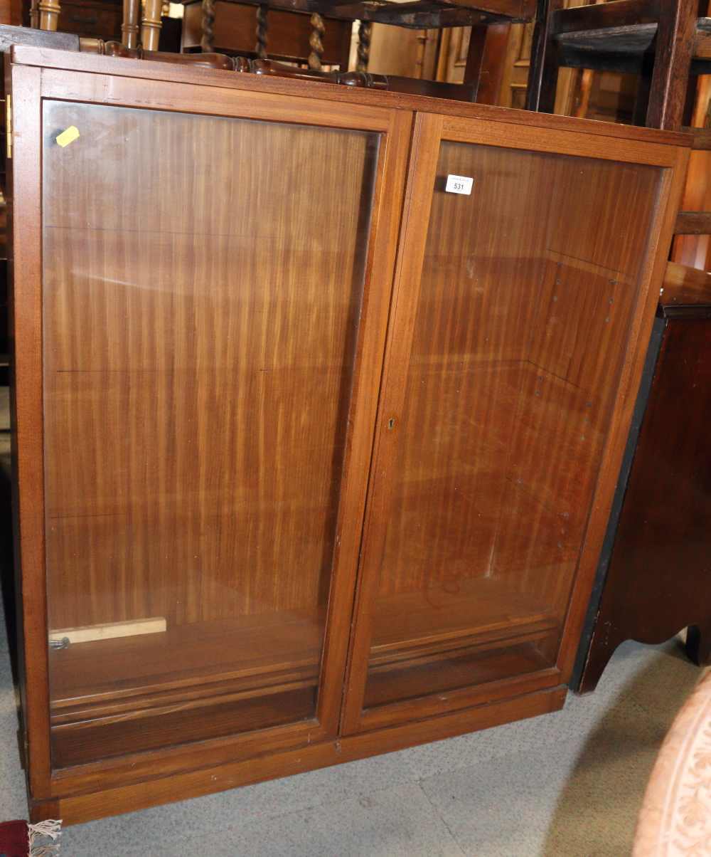 A teak bookcase with adjustable shelves enclosed two glazed doors, 36" wide