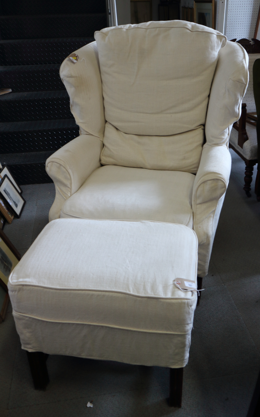 A Georgian design wing chair with loose cream covers, on reeded and stretchered supports, and