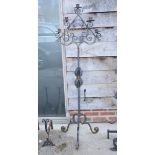 A wrought iron standard lamp with scrolled foliate decoration, on tripod base, and a similar wrought