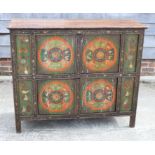 A "Tibetan" painted panelled cupboard with sacred symbols enclosed four doors, on stile supports,