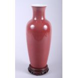 A Chinese sang de boeuf glazed porcelain baluster vase, on integral pierced hardwood stand, 13"
