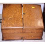 An Edwardian oak stationery cabinet, fitted two sloping doors and a lower drawer