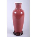 A Chinese sang de boeuf glazed porcelain baluster vase, on integral pierced hardwood stand, 13" high