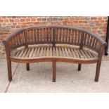 A curved slatted teak garden bench, 62" wide