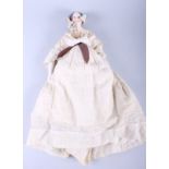 A mid 19th century articulated porcelain doll, with painted limbs, dressed in a cream outfit (a/f)