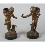 A pair of early 20th century brass spill holders, in the form of putti, each on circular marble