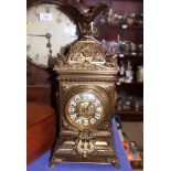 A 19th century brass cased mantel clock with enamelled black painted numerals, cast with floral