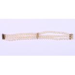 A three-strand cultured pearl bracelet with 9ct gold clasp and mounts, 7 3/4" long