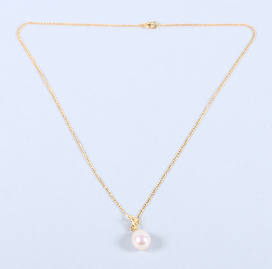 A yellow metal mounted pearl pendant, on a travelink chain