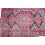 A Turkish tribal rug with central medallion on a black ground and florette border, 76" x 51"