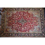 A Kashan design rug decorated floral motifs on a red ground, 84" x 58" approx