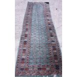 A modern Bokhara runner of traditional design on a green ground, 115" x 38" approx