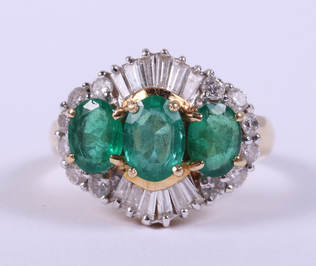 An 18ct gold ring set three graduated emeralds flanked baguette and brilliant cut diamonds, ring