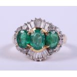 An 18ct gold ring set three graduated emeralds flanked baguette and brilliant cut diamonds, ring