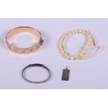A rolled gold bangle with engraved decoration, a child's silver bangle, an ivory bead necklace and a
