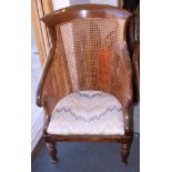 An early 20th century mahogany framed scroll arm cane chair, with fitted pad seat, on turned