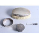 A silver backed clothes brush, a silver trinket box, a silver bracelet and a silver mounted button