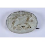 A Chinese lotus carved jade oval brooch with silver mount, 2 1/4" max dia