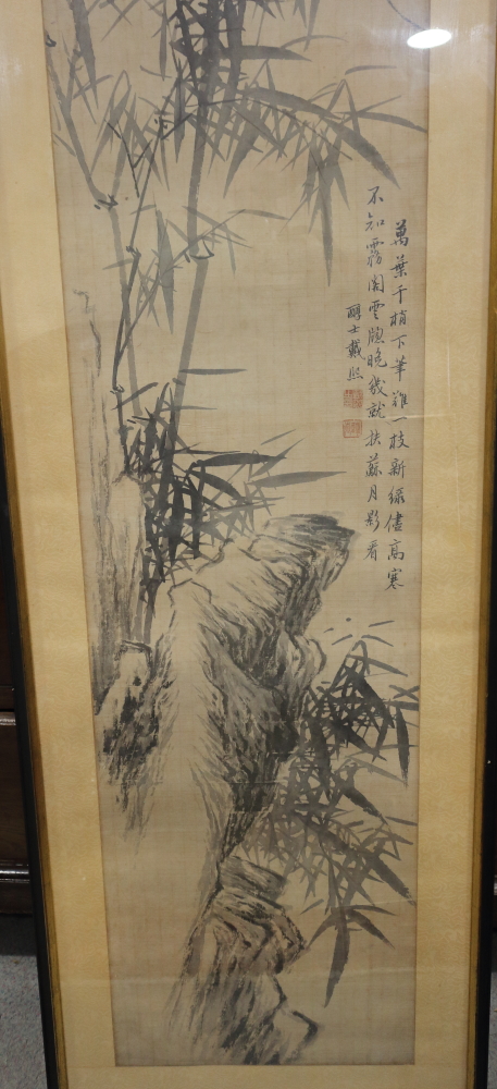 A Chinese ink drawing of a landscape with rocks and bamboo, 46 1/2" x 13", in strip frame