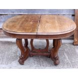 A Continental walnut extending dining table with three extra leaves, on shaped supports united by