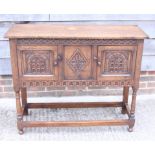 A carved oak side cabinet enclosed two doors, on turned and stretchered supports, 30" wide