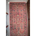 A Persian tribal rug with vase of flower design on a red ground, 55" x 25" approx