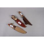 Two 20th century horn handled Bowie type knives and an ash handled knife, each in leather sheath