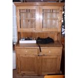 A pine dresser with glazed upper section enclosed two doors over two drawers and cupboards, on block