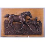 A relief moulded bronze plaque depicting a mare and foal, on wooden mount