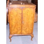 A figured walnut and banded cocktail cabinet with fitted interior, on cabriole supports, 28" wide