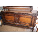 A carved oak cupboard enclosed two doors, on turned supports, 53" wide