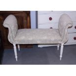 A window seat of Georgian design, upholstered in a cream fabric, on fluted supports